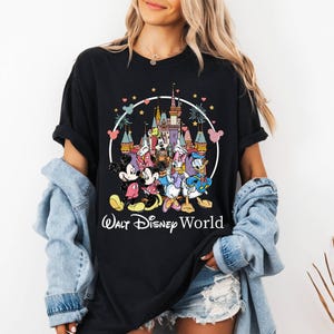 Puede incluir: Camiseta negra con un gr&aacute;fico colorido de Mickey Mouse, Minnie Mouse, Donald Duck, Goofy y Pluto frente al Castillo de Cenicienta. El texto "Walt Disney World" est&aacute; impreso debajo del gr&aacute;fico.