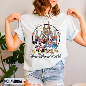 Puede incluir: Una camiseta azul claro con una ilustraci&oacute;n de estilo vintage de Mickey Mouse, Minnie Mouse, Donald Duck, Goofy y Pluto frente al Castillo de Cenicienta. El texto "Walt Disney World" est&aacute; impreso debajo de la ilustraci&oacute;n.