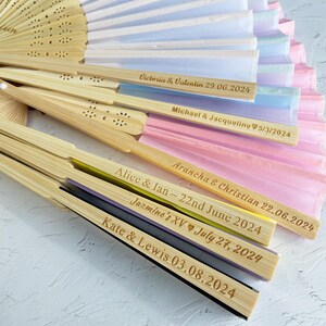 May include: A set of six bamboo hand fans with colorful silk paper and personalized inscriptions. The inscriptions include names and dates, such as "Victoria & Valentin 29.06.2024" and "Alice & Ian~22nd June 2024".