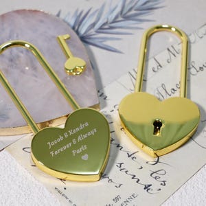 May include: Two gold heart-shaped padlocks with keys. One padlock has the inscription "Jacob & Kendra Forever & Always Paris".