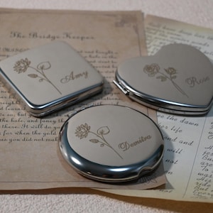 May include: Three silver compact mirrors with engraved floral designs and personalized names: Amy, Rose, and Demitra. The mirrors are on a vintage paper background.