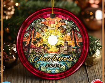 May include: A round ceramic Christmas ornament featuring a stained-glass style illustration of a tropical sunset with palm trees, buildings, and water. The text Charlevoix and the year 2025 are printed in gold. It has a red border and a gold string.