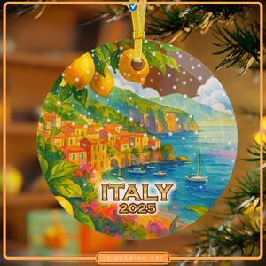 Pode incluir: Um enfeite de Natal redondo com uma cena de uma vila costeira italiana, com o texto "ITALY 2025". O enfeite tem uma fita dourada para pendurar e apresenta limões e folhas verdes no topo.