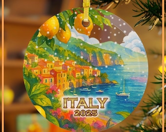 May include: A round Christmas ornament featuring a coastal Italian village scene with the text "ITALY 2025." The ornament has a gold ribbon for hanging and includes lemons and green leaves at the top.