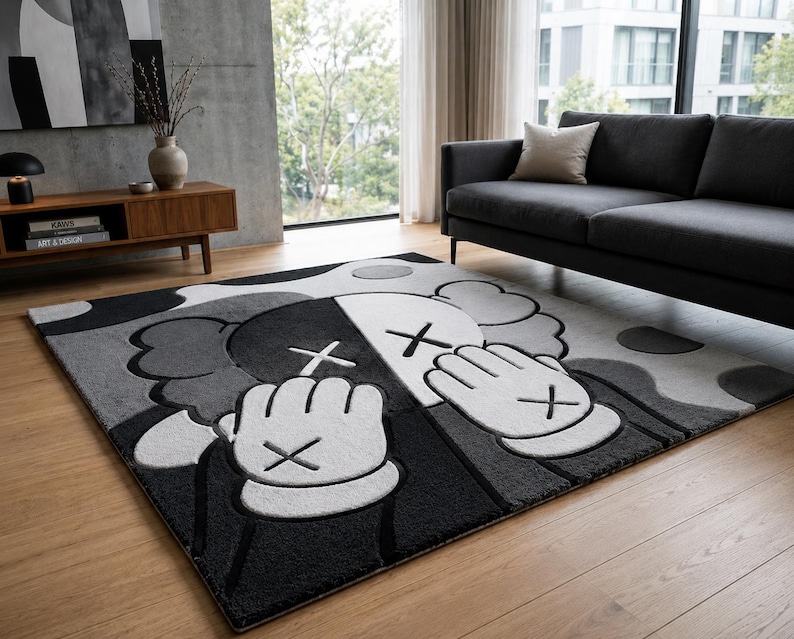 Pu&ograve; includere: Un tappeto rettangolare con una grande grafica stilizzata di un personaggio dei cartoni animati in tonalit&agrave; di nero, bianco e grigio. Il design raffigura una figura con mani guantate che coprono il volto, caratterizzata da occhi a X.