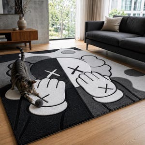 Pu&ograve; includere: Un tappeto rettangolare con un design grafico nero, bianco e grigio raffigurante due mani in stile cartone animato con occhi a forma di X e dita che coprono il volto. Il tappeto ha una superficie testurizzata su un pavimento in legno chiaro.