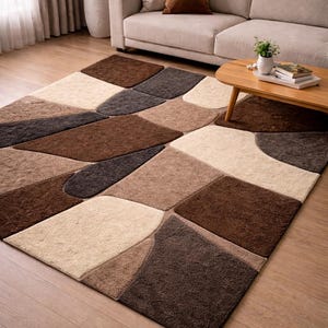 May include: A rectangular area rug with a geometric pattern in shades of brown, beige, and gray. The rug is placed on a wooden floor in a living room setting. The rug's design features irregular shapes and varying textures.