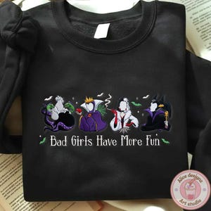May include: Black sweatshirt featuring four cartoon villain characters with the text "Bad Girls Have More Fun" in white and green. The characters are in purple, white, and black.