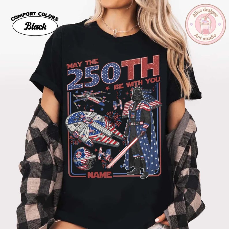 May include: Black Comfort Colors t-shirt with a graphic featuring Darth Vader, spaceships, and fireworks in red, white, and blue. The text reads "May the 250th Be With You" and "NAME:" at the bottom.