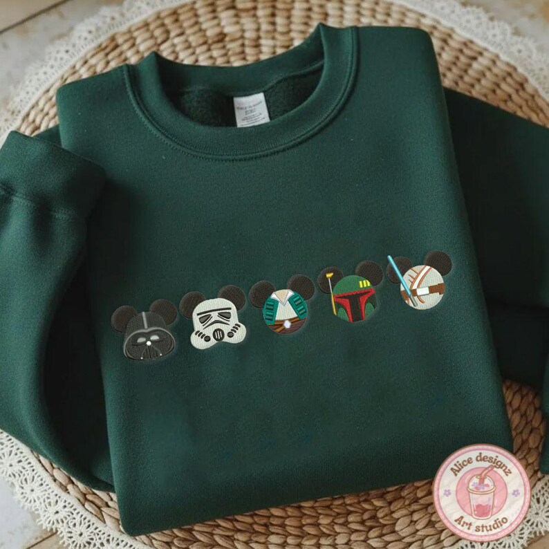 May include: Dark green sweatshirt featuring embroidered character designs. The design includes Darth Vader, a Stormtrooper, and other characters. The sweatshirt has a crew neck and long sleeves. The design is in the style of Mickey Mouse.