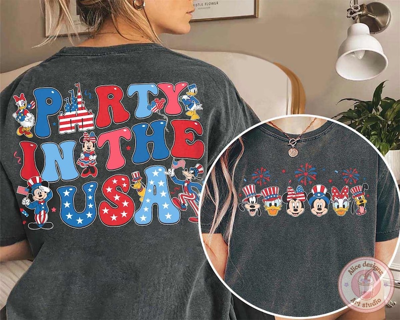 Peut inclure: T-shirt gris fonc&eacute; avec l'inscription "Party in the USA" en rouge, blanc et bleu, orn&eacute;e de personnages de dessins anim&eacute;s. Parfait pour c&eacute;l&eacute;brer le 4 juillet ou tout &eacute;v&eacute;nement patriotique.