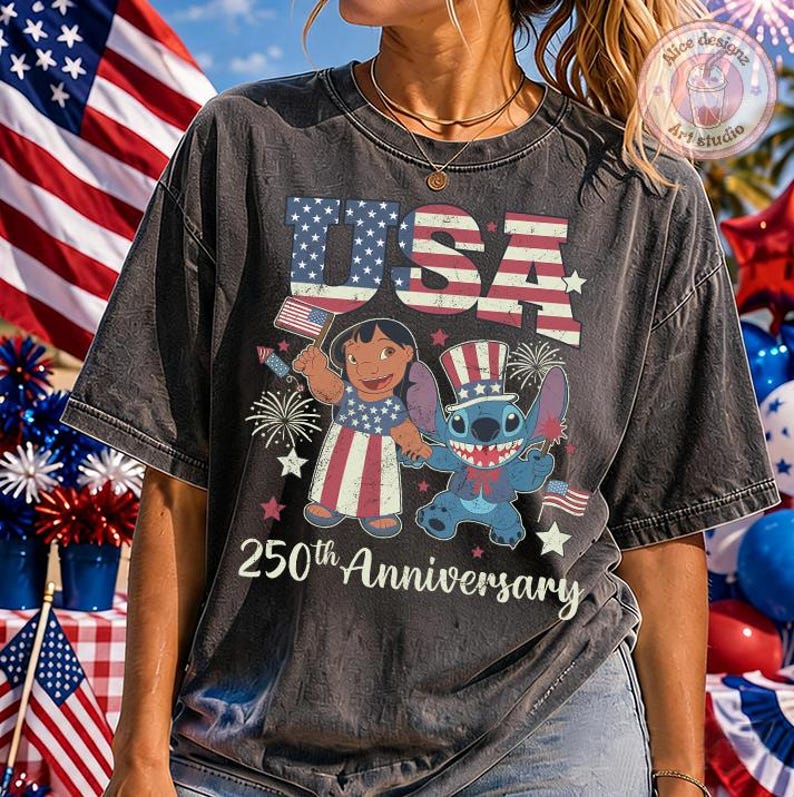May include: A charcoal grey t-shirt featuring a graphic of Lilo and Stitch dressed in patriotic attire. The design includes the text USA and 250th Anniversary, surrounded by American flag motifs, fireworks, and stars in red, white, and blue colors.