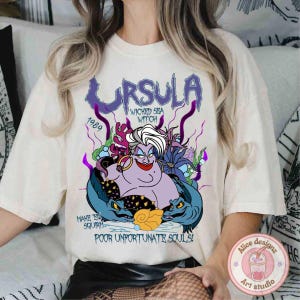 May include: White t-shirt with a graphic print of Ursula from The Little Mermaid. The graphic features Ursula in her sea witch form with the text "Ursula, 1989, Wicked Sea Witch, Make 'em Squirm, Poor Unfortunate Souls!"