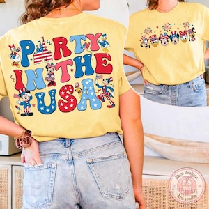 Peut inclure: T-shirt jaune avec l'inscription "PARTY IN THE USA" en rouge, bleu et rose, avec des personnages de dessins anim&eacute;s. Le t-shirt pr&eacute;sente &eacute;galement une rang&eacute;e de personnages de dessins anim&eacute;s avec des feux d'artifice.
