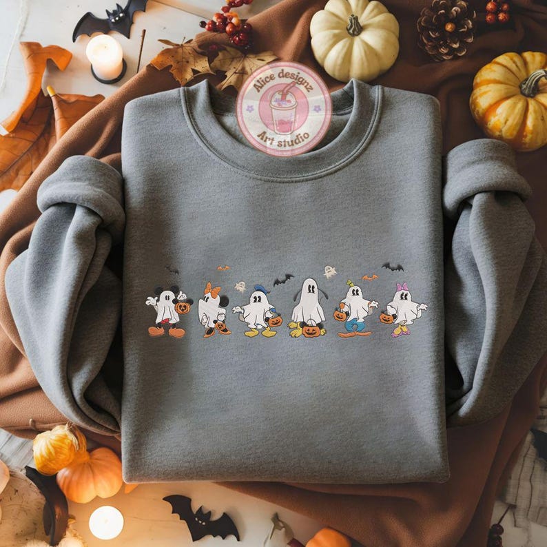 K&ouml;nnte beinhalten: Ein graues Sweatshirt mit einem Halloween-Motiv. Das Design zeigt Cartoon-Geister, die als beliebte Charaktere verkleidet sind, K&uuml;rbisse halten und von Flederm&auml;usen begleitet werden. Das Sweatshirt hat lange &Auml;rmel und einen Rundhalsausschnitt.