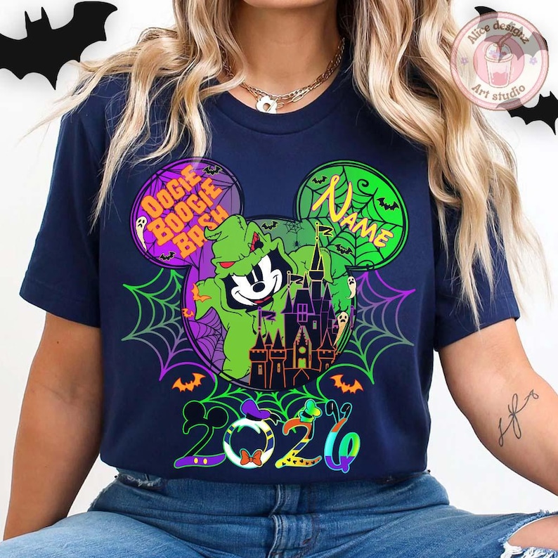 May include: Navy blue t-shirt featuring a Halloween-themed design. The graphic includes a cartoon character in a green costume, a haunted castle, spiderwebs, and the text "Oogie Boogie Bash" and "2026". The design is in a Mickey Mouse head shape.
