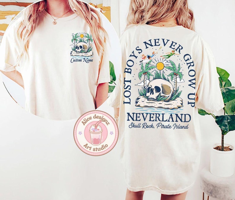 May include: A white t-shirt with a graphic print of a skull and palm trees. The text "Lost Boys Never Grow Up" is printed in blue on the back of the shirt. The text "Neverland Skull Rock, Pirate Island" is printed below the graphic.