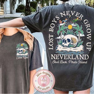 May include: Black t-shirt with a graphic print of a skull and crossbones with the text "Lost Boys Never Grow Up Neverland Skull Rock, Pirate Island".