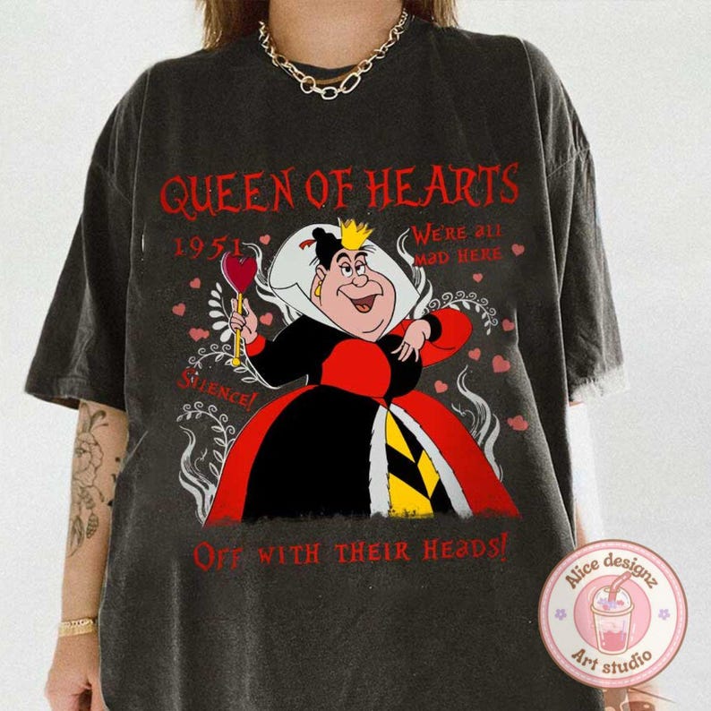 May include: A black t-shirt with a graphic print of the Queen of Hearts from Alice in Wonderland. The graphic features the Queen holding a playing card heart and the text "Queen of Hearts", "1951", "We're all mad here", "Silence!" and "Off with their heads!"