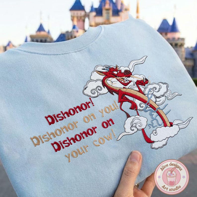 May include: Light blue sweatshirt with embroidered red dragon design and the text "Dishonor! Dishonor on you! Dishonor on your cow!" The dragon is red and tan with white clouds. The sweatshirt is held by a hand.
