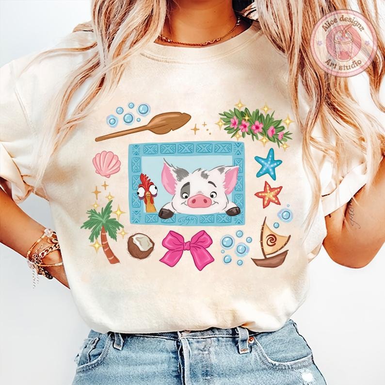 Puede incluir: Camiseta color crema con un cerdo y un gallo de dibujos animados dentro de un marco azul, rodeada de elementos tropicales como una palmera, estrellas de mar y un lazo rosa. El dise&ntilde;o incluye una cuchara de madera, burbujas y un peque&ntilde;o barco.