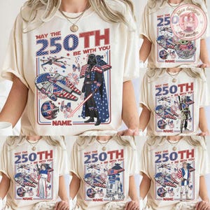 May include: Cream-coloured t-shirts with a patriotic Star Wars design. The shirts feature the text "MAY THE 250TH BE WITH YOU" and various Star Wars characters and symbols, including Darth Vader, the Millennium Falcon, and X-wing fighters.