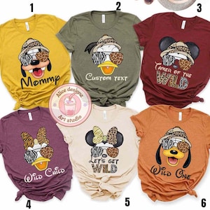 May include: Six different t-shirts with various Disney characters wearing safari hats and sunglasses. The shirts are in different colors, including yellow, green, red, purple, beige, and orange. The text on the shirts includes "Mommy", "Custom Text", "Tamer of the Wild", "Wild Child", "Let's Get Wild", and "Wild One".