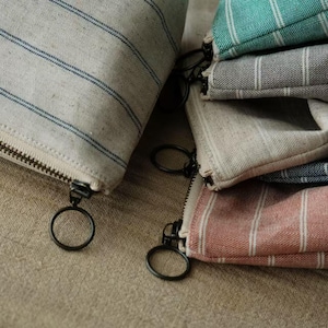 May include: Five striped fabric pouches with zipper closures. The pouches are in various colors, including beige, gray, teal, blue, and pink.