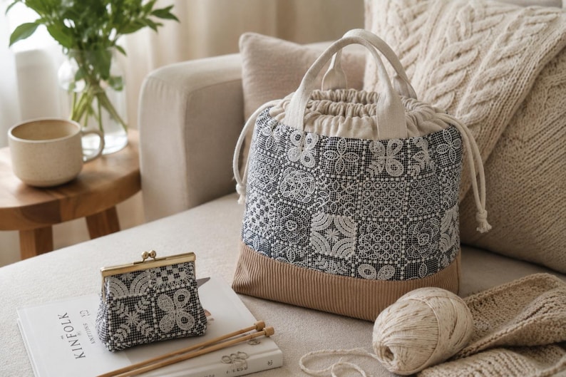 Peut inclure: Un sac seau &agrave; cordon et un porte-monnaie assorti, tous deux en tissu gris fonc&eacute; avec un motif floral blanc rappelant la dentelle et une base beige unie. Le sac poss&egrave;de deux anses et des cordons de serrage blancs pour la fermeture.