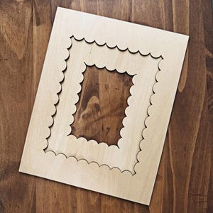 May include: A wooden frame with a scalloped edge. The frame is unfinished and has two layers, creating a double frame effect.