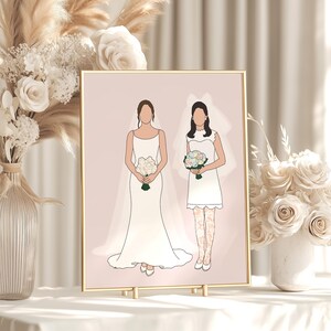 May include: A framed illustration of two brides in wedding attire, each holding a bouquet. One wears a long gown, the other a shorter dress with lace stockings. The artwork is set against a pale pink backdrop, with a gold frame.
