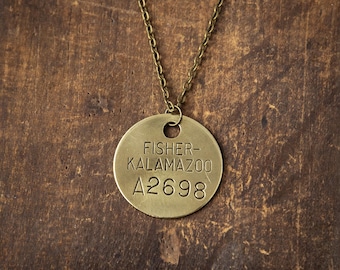 May include: A brass necklace with a round tag that reads "FISHER-KALAMAZOO A2698".