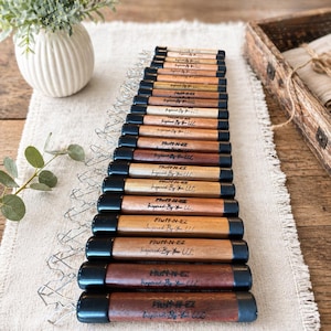 May include: A collection of wooden tools with black end caps arranged in a row. Each tool features the text Fluff-N-EZ and Inspired By You LLC printed on the surface. The tools vary in wood grain color from light tan to dark brown tones.