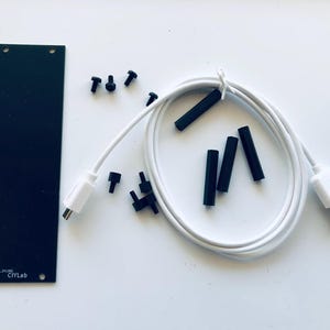 May include: A black rectangular panel with two holes, small black screws, and black cylindrical components. A white USB cable with a micro USB connector and a standard USB connector is also included. The text "CIYLab" is visible on the panel.
