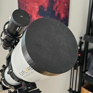 May include: A white telescope with a black lens cap and the text "Explore Scientific" on the side.