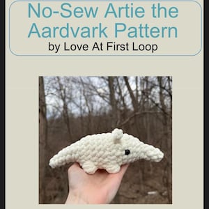 Può includere: Un giocattolo di formichiere all'uncinetto, bianco sporco, con occhi neri e un lungo muso. Il testo "No-Sew Artie the Aardvark Pattern by Love At First Loop" è visualizzato sopra il giocattolo. Il formichiere è tenuto in mano da una persona.