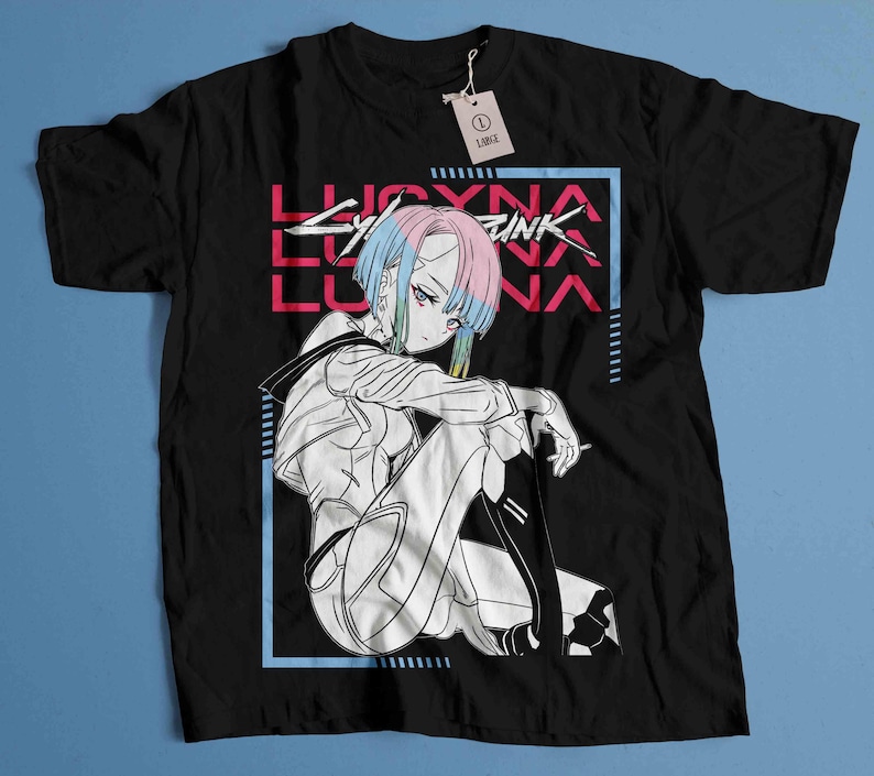 Peut inclure: T-shirt noir avec un graphisme de personnage d'anime aux cheveux bleus et roses, et le texte "LUCYNA CYBERPUNK". Le design est encadr&eacute; dans un rectangle bleu. Une &eacute;tiquette indique "LARGE".