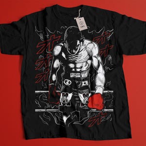 May include: Black t-shirt featuring a detailed illustration of a muscular boxer in a fighting stance. The graphic is in black and white with red accents, including the boxer's gloves and Japanese text. A tag indicates the size is large.