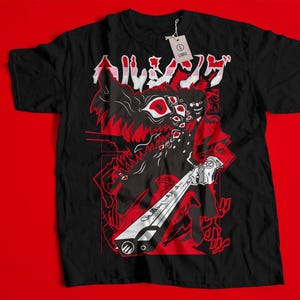 Puede incluir: Camiseta negra con un estampado gráfico rojo y blanco de un monstruo sosteniendo un arma. El texto "アルマジロ" está impreso en la camiseta.