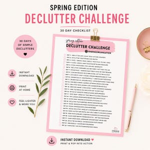 May include: A 30-day declutter challenge checklist printed on white paper with a pink border, held by a gold binder clip. The text lists daily tasks from day 1 to 30. Accompanying icons include a download arrow, printer, heart, and a green leaf sprig.