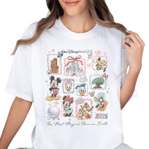 A white t-shirt with a collage of Disney characters and landmarks, including Mickey Mouse, Minnie Mouse, Donald Duck, Goofy, and a castle. The text on the t-shirt says "Disney World" and "The Most Magical Place on Earth".