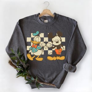 A gray sweatshirt with a graphic design featuring two cartoon characters, Mickey Mouse and Donald Duck, standing together.