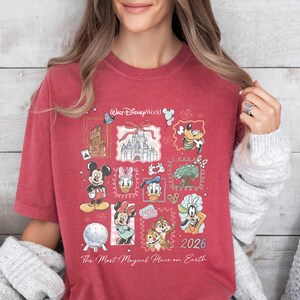 A woman wearing a red t-shirt with Disney characters and the text "The Most Magical Place on Earth" printed on it.