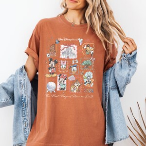 A woman wearing a t-shirt with Disney characters and a denim jacket, smiling and posing for the camera.