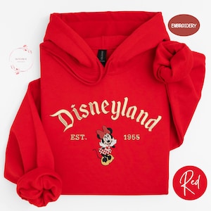 A red hoodie with the text "Disneyland" and a Minnie Mouse embroidered on it, along with the text "EST. 1955" below the Minnie Mouse.