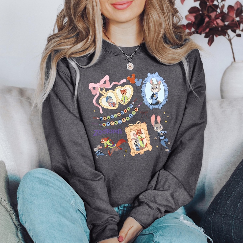 A woman wearing a gray sweatshirt with various cartoon animal characters and designs printed on it, sitting on a couch.