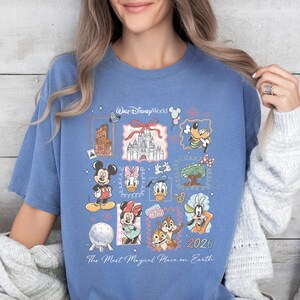 A woman wearing a blue t-shirt with a collage of Disney characters and a text that says "The Most Magical Place on Earth" printed on it.