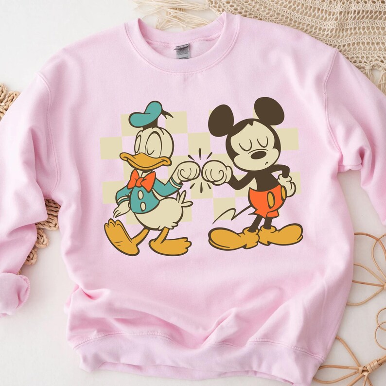 A pink sweatshirt with a cartoon image of Mickey Mouse and Donald Duck.