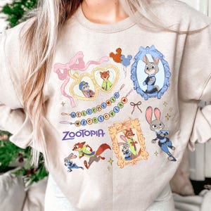A person wearing a white sweatshirt with various cartoon animal characters and a welcoming message printed on it.