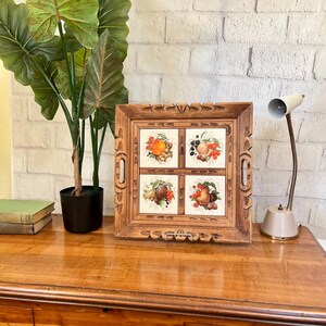 May include: A wooden serving tray with four ceramic tiles depicting fruit. The tiles are framed in a carved wooden frame. The tray has two handles on the sides.